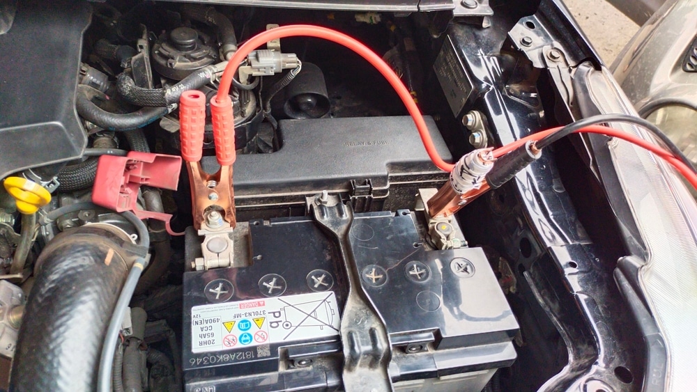 Identifying Car Start Issues | Lonsdale Auto Works' Expert Advice. Close up image of car battery with jumper cables hooked to it because the car won’t start.